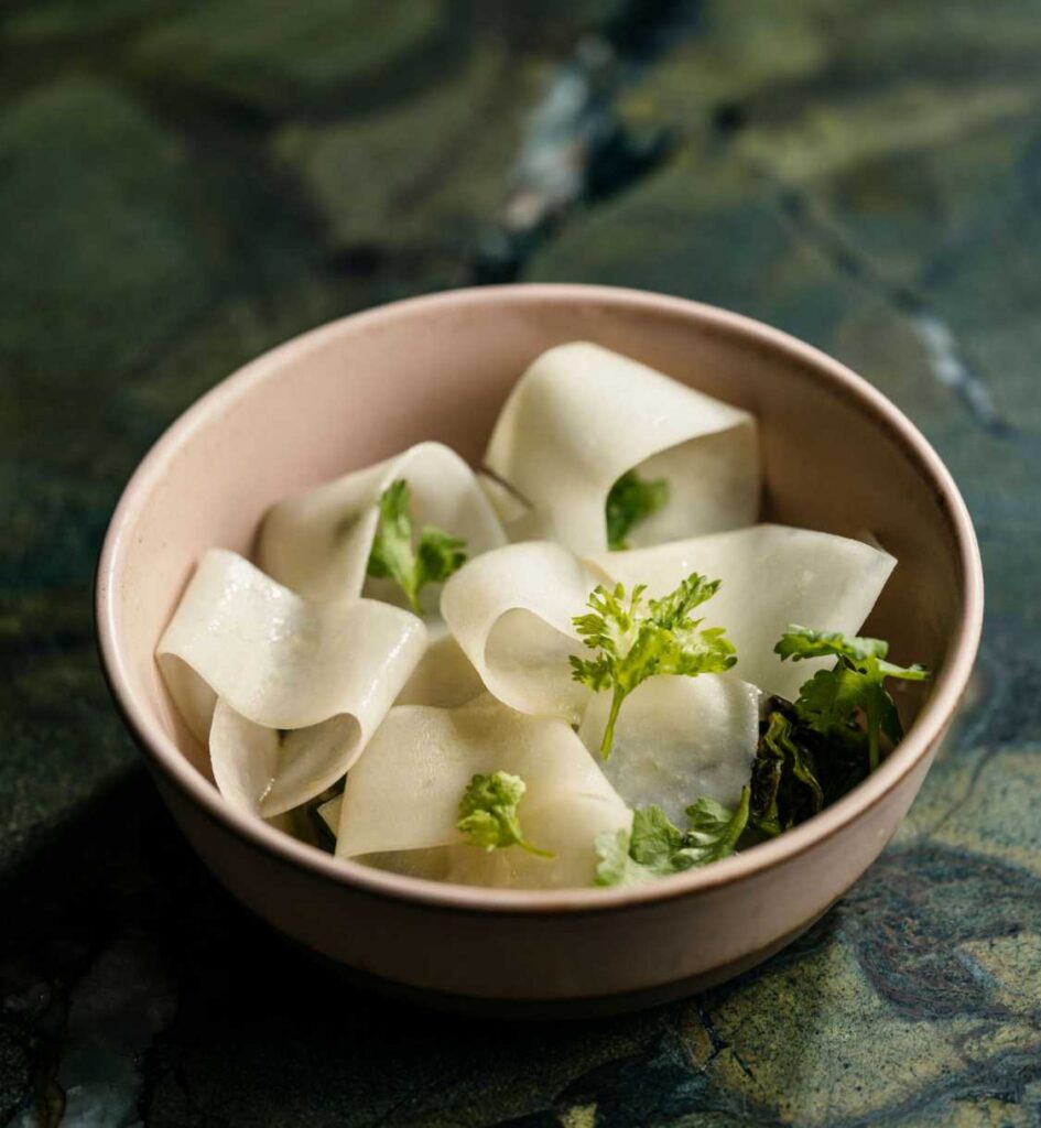 Dish garnished with fresh herbs in a light pink bowl.